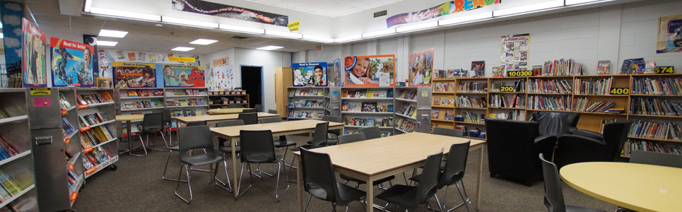 St. Paul Catholic School library with wall-to-wall bookshelves and tables and chairs in the middle.