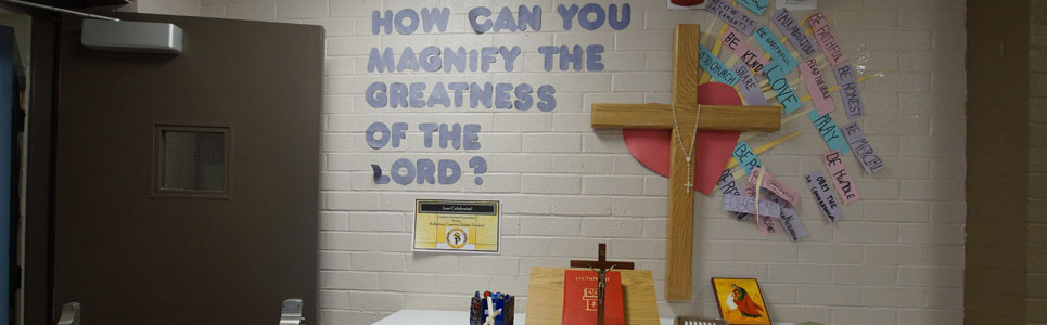 St. Paul Catholic School alter. The wall reads; "How can you magnify the greatness of the Lord? to the left of a cross.